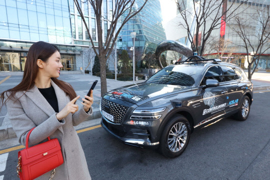 LG유플러스 모델이 17일 서울시 상암 5G 자율주행 시범지구에서 모바일 앱으로 5G 자율주행차 'A1(에이원)'을 인근 공영주차장으로 보내고 있다.    LG유플러스 제공